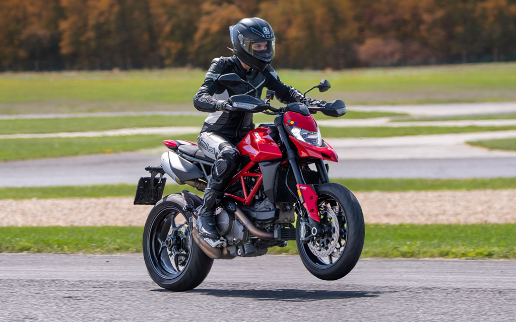 Alina Cateyka pulling a wheelie on a red motorcycle