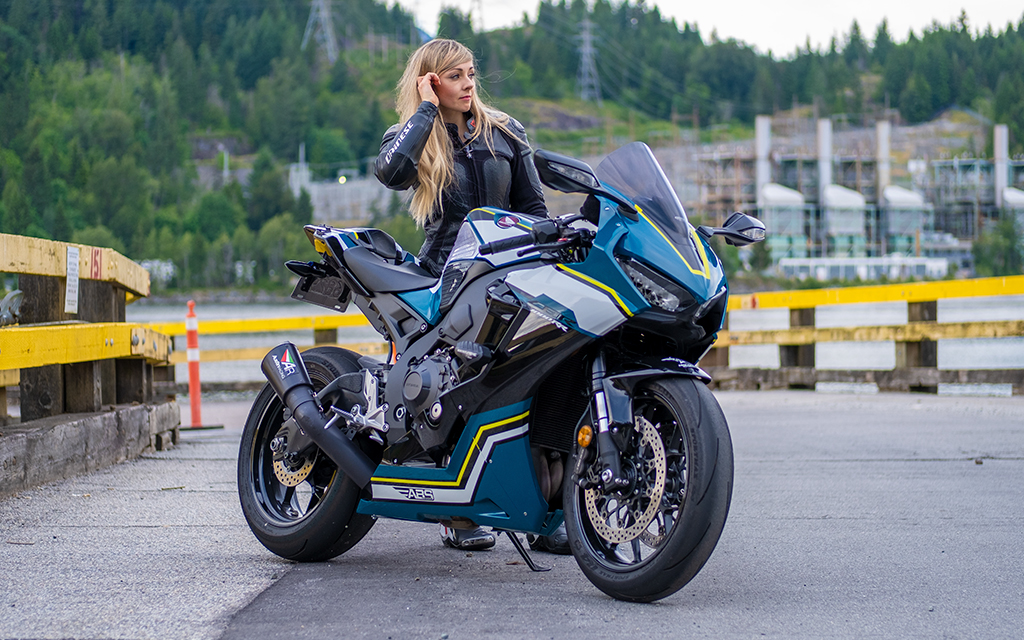 Amber Spencer standing next to a blue and grey motorcycle