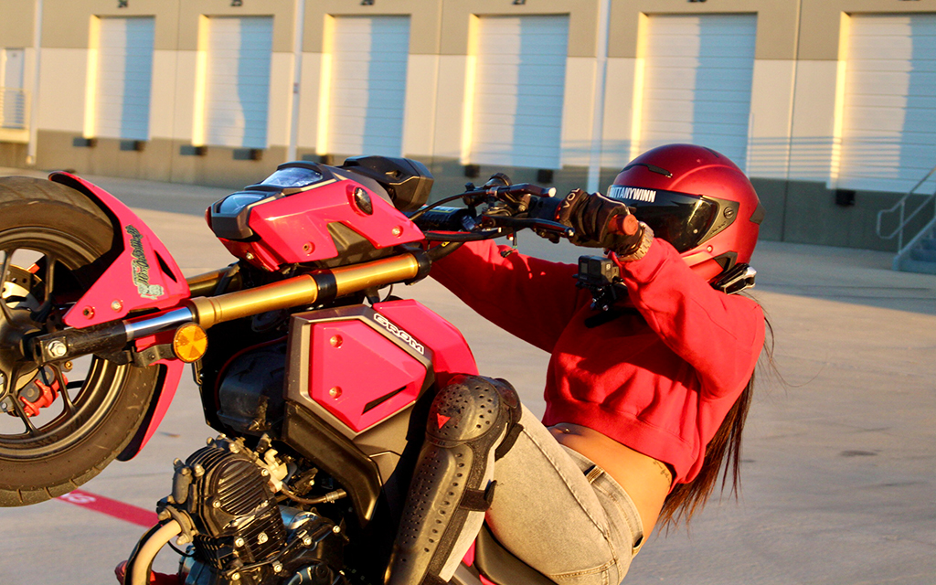 Brittany Winn doing a wheelie on a pink motorcycle