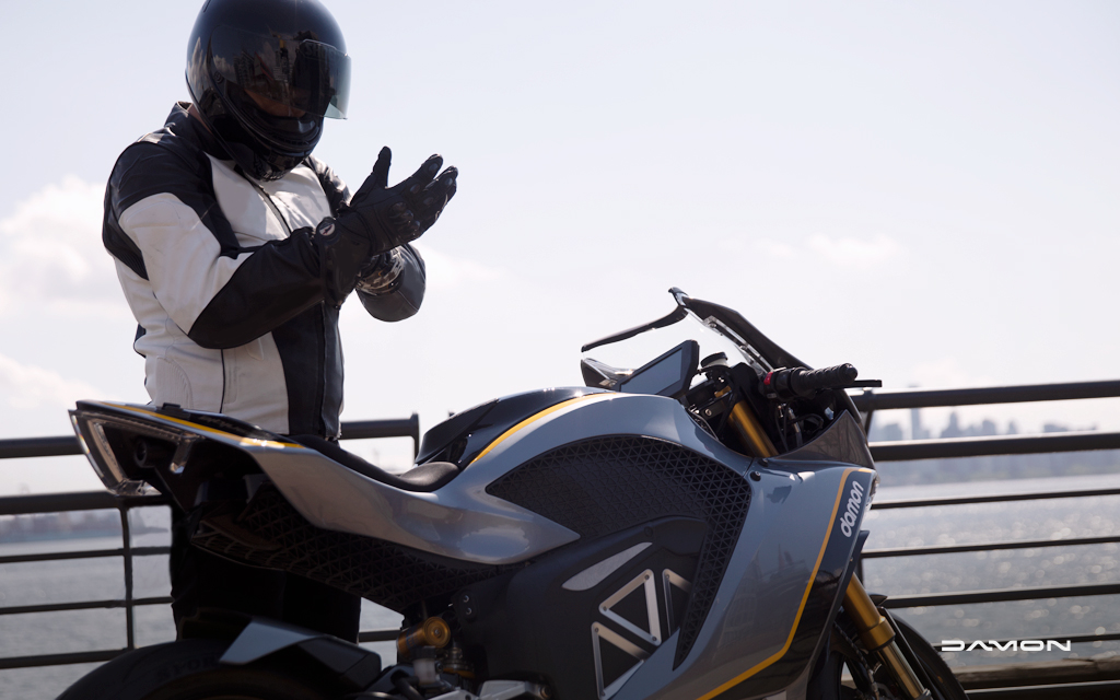 motorcycle rider putting on gloves next to damon hypersport premier prototype