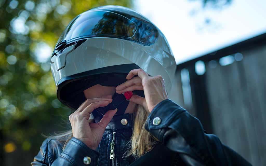 women adjusting her motorcycle helmet